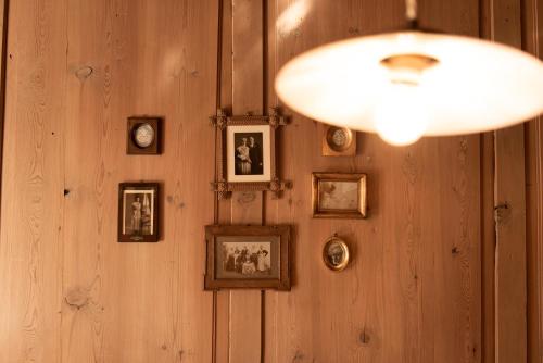 a wall with pictures on a wooden wall with a light at Hotel Heubad in Fiè