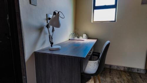 a desk with a lamp and a chair in a room at Ondjo Yetu in Benoni