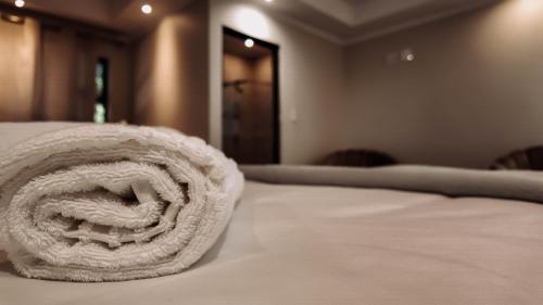 a white bed with a rolled up towel on it at Ondjo Yetu in Benoni