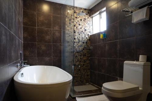 y baño con bañera, aseo y ducha. en The Zehneria Hotel, en Nairobi