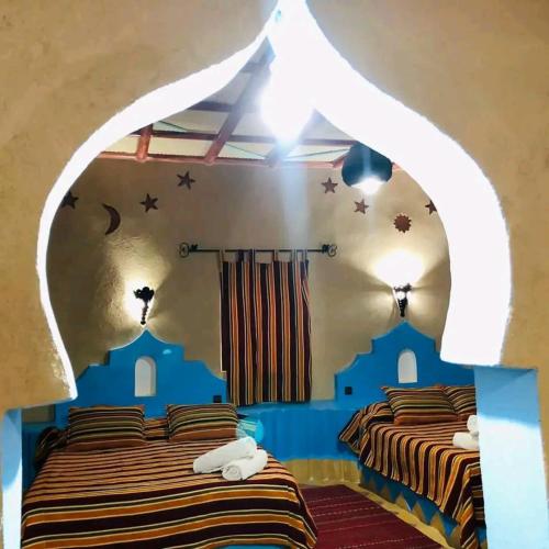 two beds in a room with an arched window at Riad Kasbah le Touareg in Merzouga
