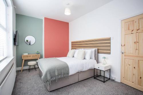 a bedroom with a large bed and a red wall at Meldon Terrace Parking Wi-fi in Woodhorn