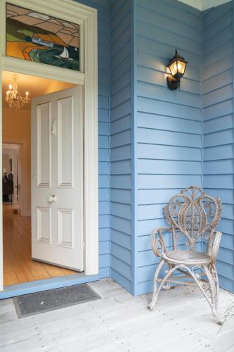 a blue house with a chair next to a door at Riverside Charm - A stone's throw to the river in Barwon Heads