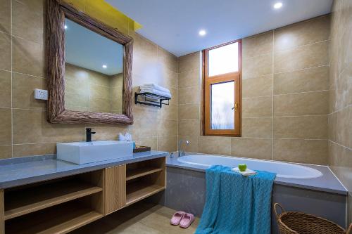 a bathroom with a tub and a sink and a mirror at Lijiang half yard hotel in Lijiang
