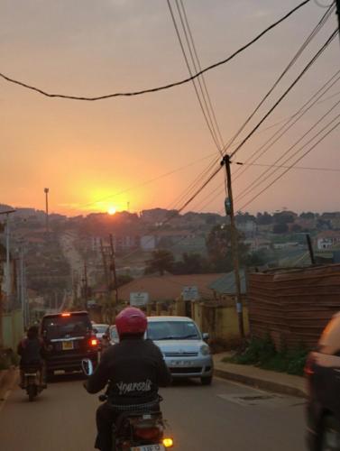 a person riding a motorcycle down a street at sunset at The Urban Oasis Ntinda in Nalakonge