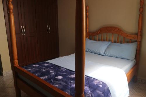 a bedroom with a bed with a wooden bed frame at The Urban Oasis Ntinda in Nalakonge