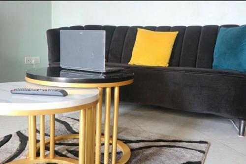 a black couch with a laptop on top of two tables at The Urban Oasis Ntinda in Nalakonge