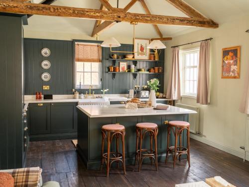 a kitchen with green cabinets and a large island with bar stools at Chapman House 3 Bedroom Luxury Retreat in Norwich