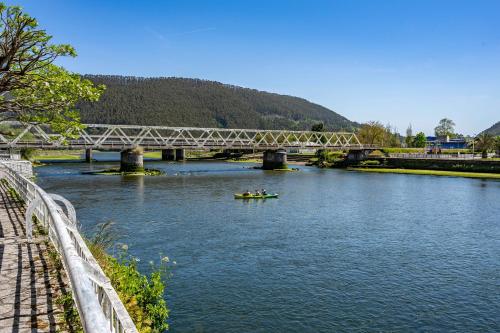 a group of people in a boat on a river under a bridge at Apartamentos El Rincón de Bustio in Bustio