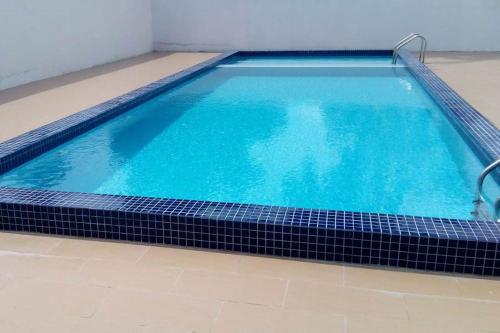 uma piscina com água azul e azulejos pretos em Royal Agate Beach Resort em Pantai Cenang