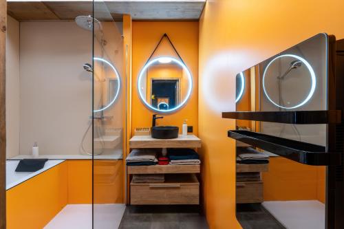 a bathroom with orange walls and a mirror at Appartement avec piscine & terrasse vue montagne in Annecy