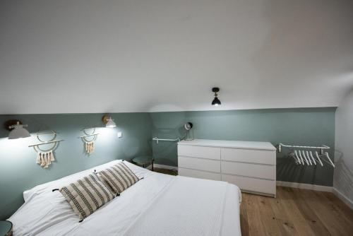 une chambre avec un lit blanc et des murs verts dans l'établissement Le duplex d'André - Un écrin cosy et design pour 2, à Lyon