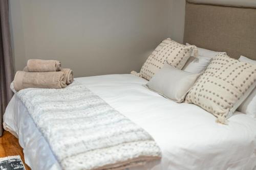 a white bed with pillows and a blanket on it at Room 1 - LEO Sky Guest House in Simondium