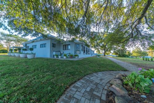 a house on a lawn with a tree overhead at Room 1 - LEO Sky Guest House in Simondium
