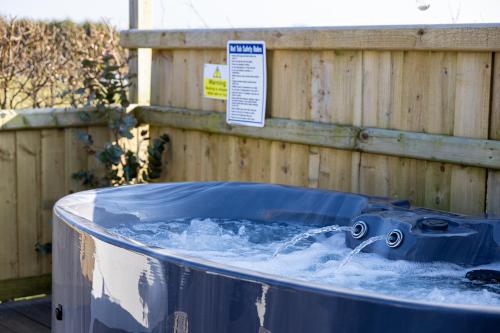 a hot tub with water in it next to a wooden fence at Willows Rest - 1 Bed Shepherds Hut - Pentlepoir in Saundersfoot