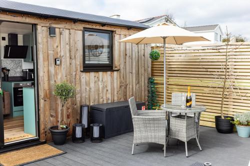 a patio with a table and chairs and an umbrella at Willows Rest - 1 Bed Shepherds Hut - Pentlepoir in Saundersfoot