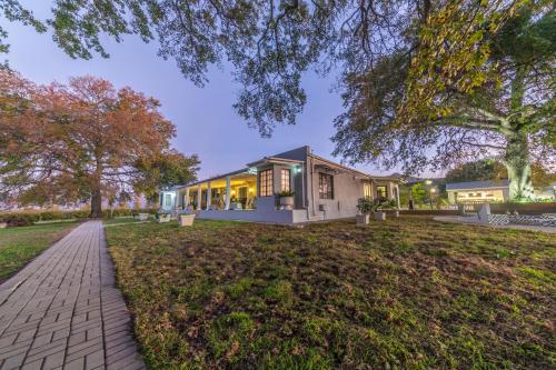 a house on a lawn in front of a house at Room 1 - LEO Sky Guest House in Simondium