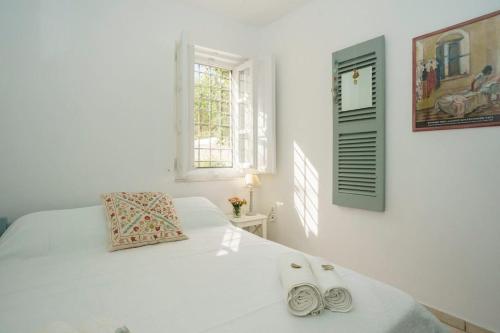 a bedroom with a white bed with two slippers on it at Nostos in Hydra
