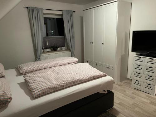 a bedroom with a bed with two pillows and a television at Ferienwohnung Anne in Großheide
