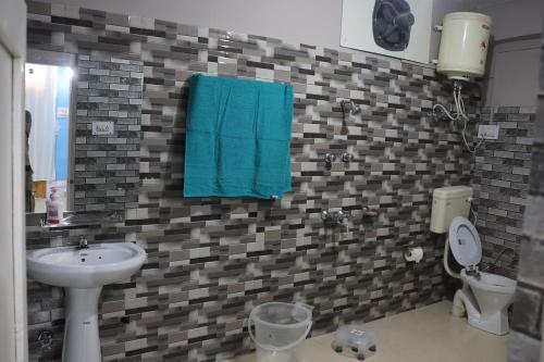 een badkamer met een wastafel, een toilet en een blauwe handdoek bij Tirthan Living Green Home Stays in Banjār