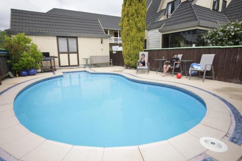 a large swimming pool with blue water in a yard at Kings Gate Motel in Nelson