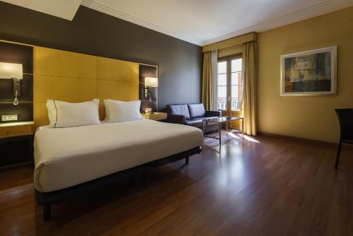 a hotel room with a large bed and a chair at Exe Almería Centro in Almería