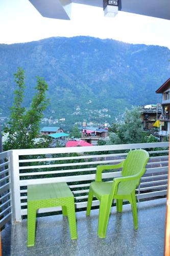 two green chairs and a table on a balcony at The Desire Manali in Manāli
