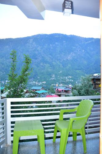 two green chairs and a table on a balcony at The Desire Manali in Manāli