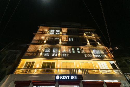 a tall building with a rest inn lit up at night at Rest Inn Hotel in Jāmb