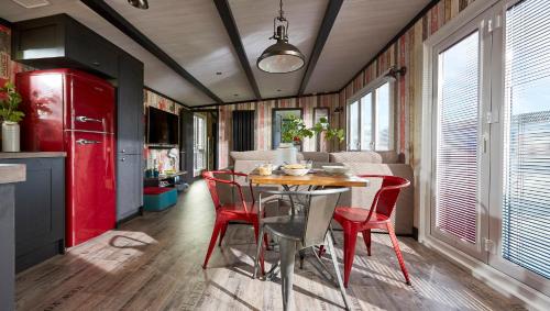 a kitchen and dining room with a table and red chairs at Mill Rythe Coastal Village in South Hayling