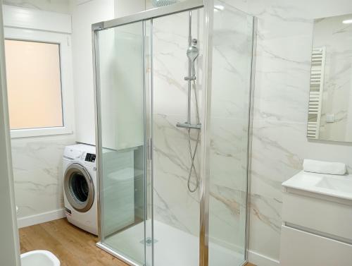 eine Glasdusche in einem Badezimmer mit Waschmaschine in der Unterkunft Apartamentos Marina Mar Vilagarcía 3000 in Villajuán