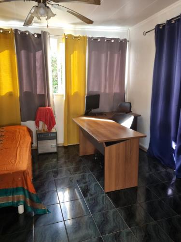 a room with a desk and a bed and curtains at CHEZ LILIANE in Saint-Denis