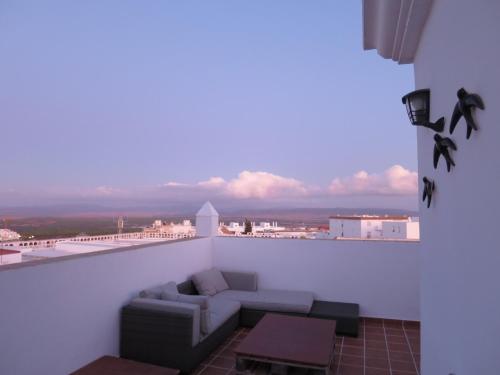 a balcony with a couch and a view of a city at Casa Susan, Penthouse apartment, view over Old Town & the Sea in Vejer de la Frontera