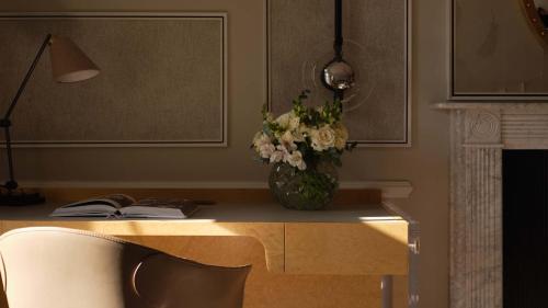 a vase of flowers on a desk with a lamp at Mandarin Oriental Hyde Park, London in London