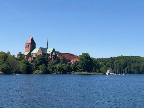a large house on the shore of a lake with a sailboat at Ferienwohnung Seeblick Ratzeburg in Ratzeburg