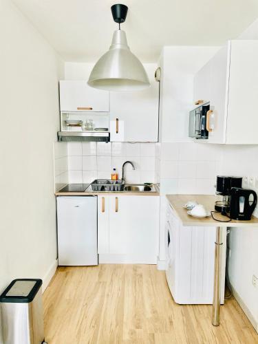 una cucina bianca con mobili bianchi e un lavello di Appartement avec place de parking et piscine a Villefranche-sur-Saône