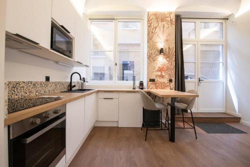 une cuisine avec des armoires blanches et une table en bois dans l'établissement Le Terrazzo - Elégant & Cosy- Pentes de la Croix Rousse, à Lyon