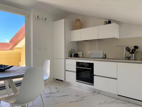 a kitchen with white cabinets and a table and chairs at Golfo Ameno Apartment in Portovenere