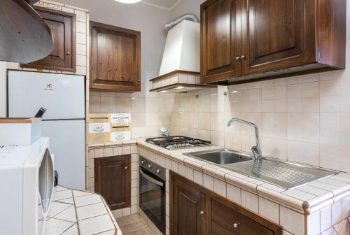 a kitchen with wooden cabinets and a sink at Travelershome Ciampino Suite in Ciampino