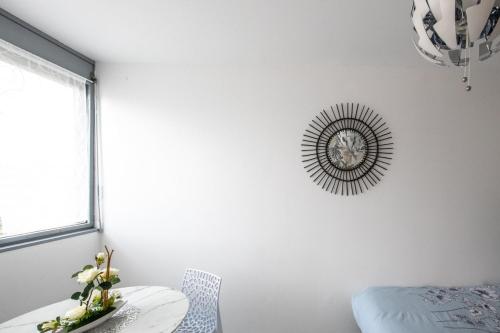 une chambre blanche avec une horloge sur le mur dans l'établissement Le Jasseron - Appartement cosy avec garage quartier PartDieu, à Lyon