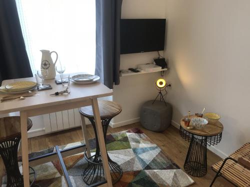 une chambre avec une table, deux tabourets et une télévision dans l'établissement La Suite de Léon appartement D - Lyon Garibaldi, à Lyon