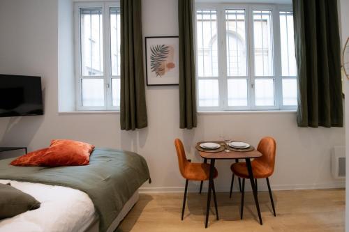 une chambre avec un lit et une table avec des chaises dans l'établissement La Suite Opéra 1 - Hypercentre proche place des Terreaux, à Lyon