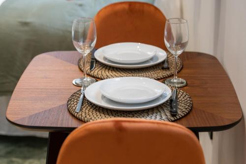 - une table avec deux assiettes et des verres à vin dans l'établissement La Suite Opéra 1 - Hypercentre proche place des Terreaux, à Lyon