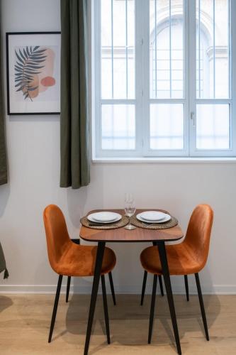 une table et deux chaises dans une pièce avec une fenêtre dans l'établissement La Suite Opéra 1 - Hypercentre proche place des Terreaux, à Lyon