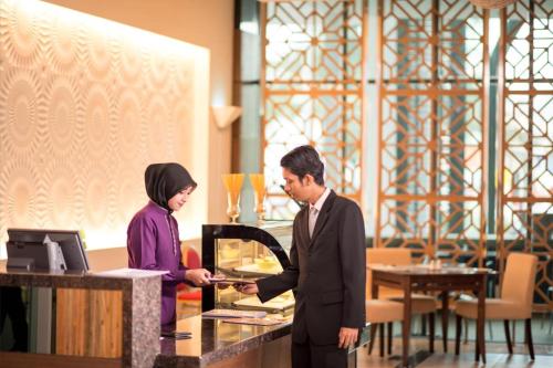
a man and a woman standing in front of a counter at Adya Hotel Langkawi in Kuah
