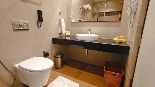 a bathroom with a white toilet and a sink at MM Legacy - A Bergamont Hotel, Kanchipuram in Kanchipuram