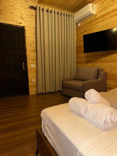 a bedroom with a bed and a chair and a television at Kantina & Ferma Dukat in Vlorë