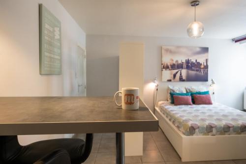 a room with a desk and a bed with a coffee mug at Le cocon des Monts d'Or in Saint-Germain-au-Mont-dʼOr