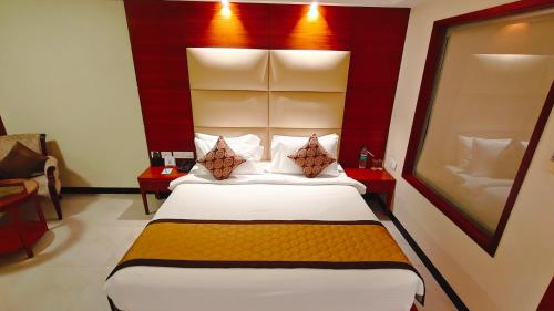 a bedroom with a large bed with a red headboard at MM Legacy - A Bergamont Hotel, Kanchipuram in Kanchipuram