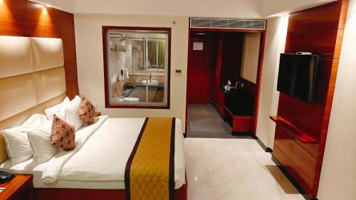 a hotel room with a bed and a television at MM Legacy - A Bergamont Hotel, Kanchipuram in Kanchipuram
